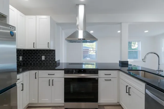 a kitchen with granite countertop a sink stainless steel appliances and cabinets
