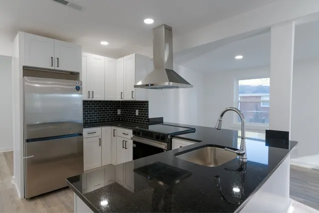 a kitchen with stainless steel appliances granite countertop a sink a stove and a refrigerator