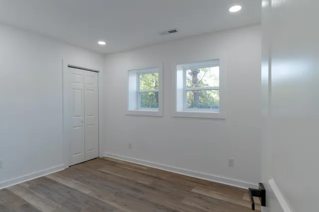 an empty room with wooden floor and windows