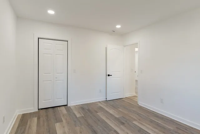 a view of an empty room with wooden floor and closet