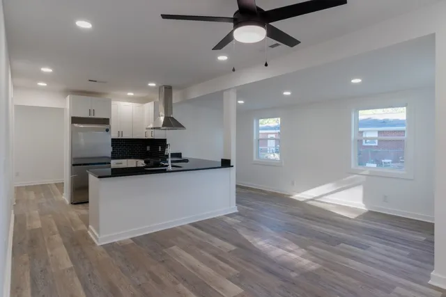 a large kitchen with stainless steel appliances a large counter top a wooden floors and a fireplace