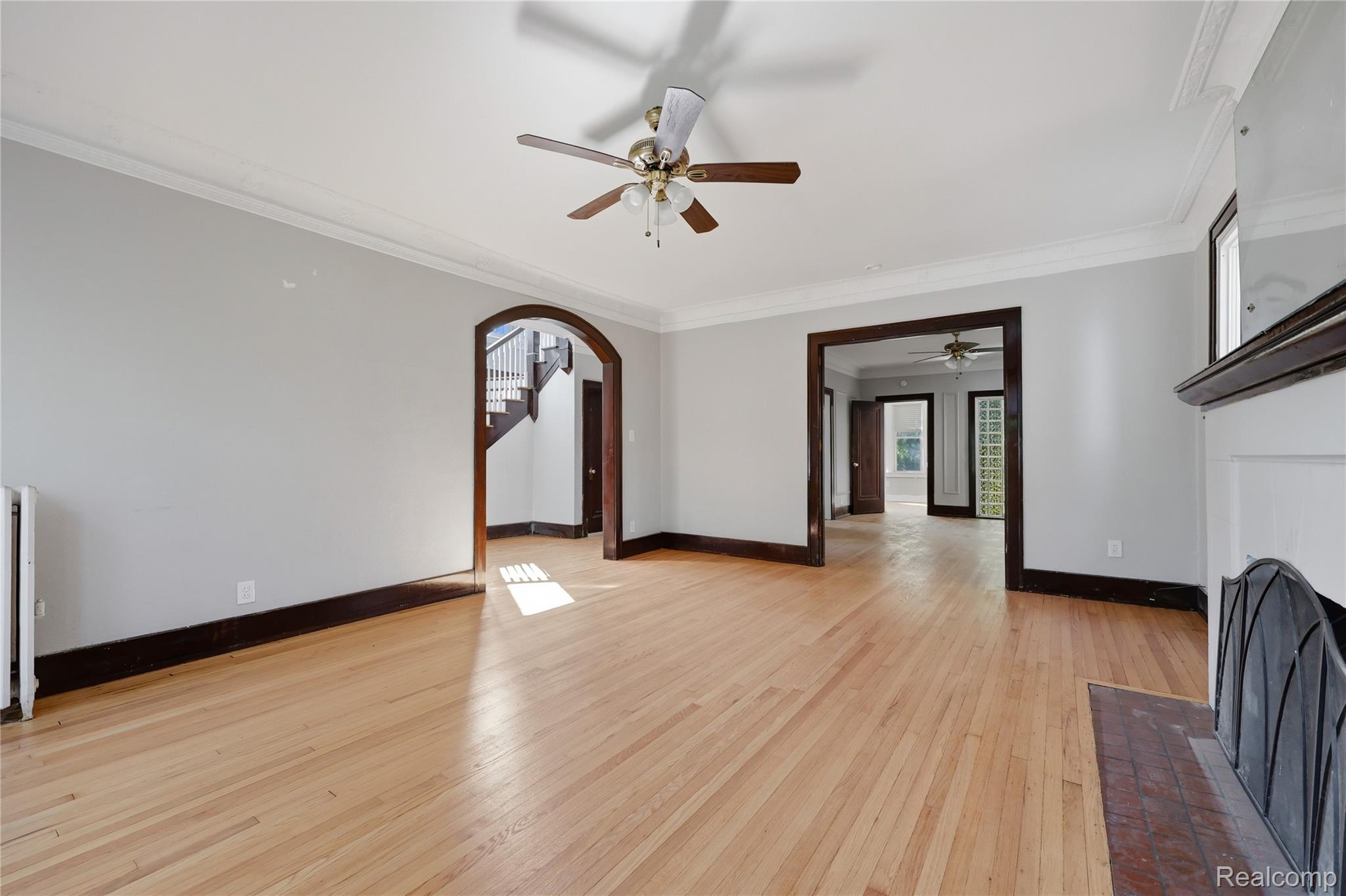 1945 Atkinson Street Detroit, MI 48206 - Photo 13 of 49 Expansive room featuring hardwood flooring, crown molding, a ceiling fan with integrated lighting, and a decorative fireplace with a tile hearth