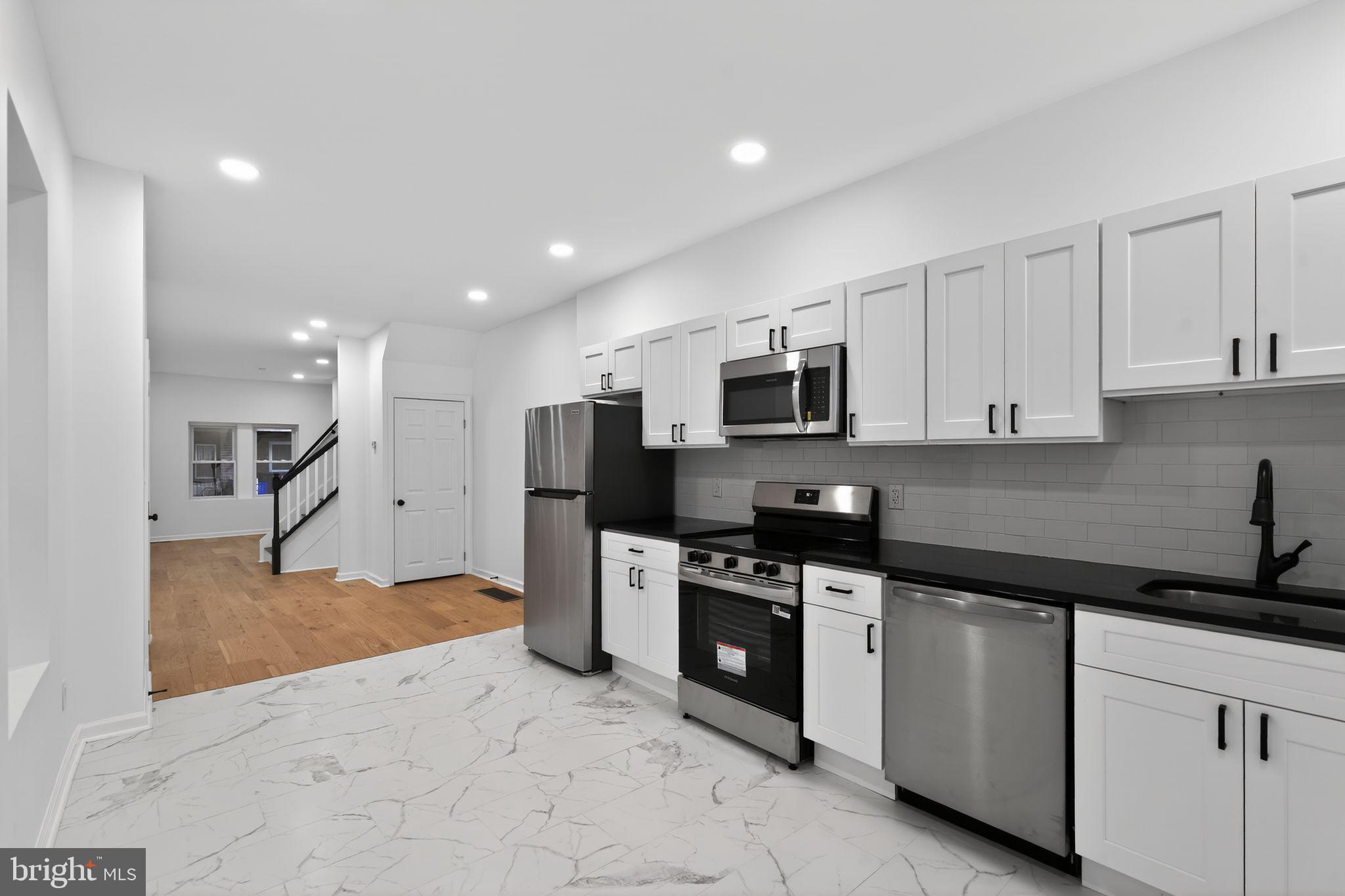 a kitchen with stainless steel appliances granite countertop a refrigerator a stove a sink and a microwave