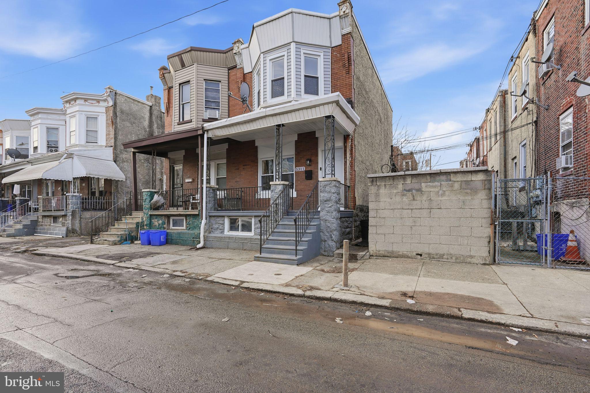 5311 Upland Street Philadelphia, PA 19143 - Photo 28 of 31 a view of a brick house with large windows and a small yard