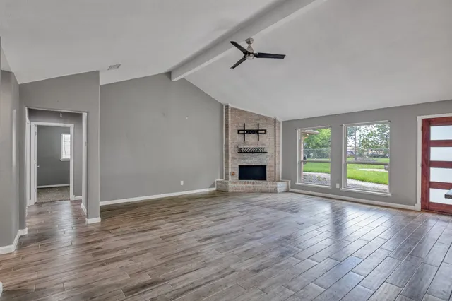 a view of an empty room with a window and wooden floor