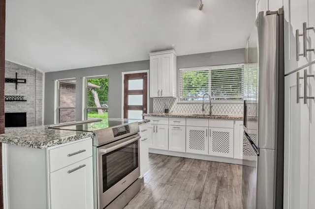 a kitchen with granite countertop white cabinets and white appliances