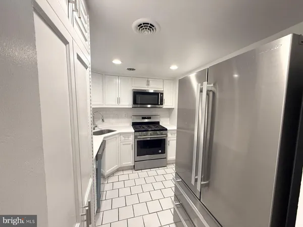 a kitchen with a refrigerator a stove top oven and a sink