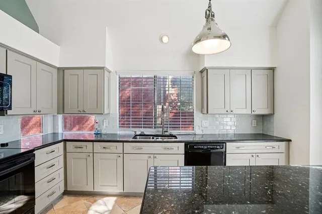 a kitchen with granite countertop a sink cabinets and stainless steel appliances
