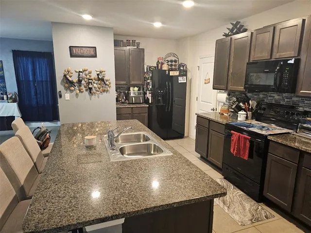 a kitchen with stainless steel appliances granite countertop a sink a stove and a refrigerator