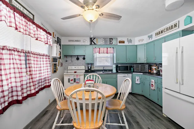 a kitchen with stainless steel appliances granite countertop a dining table chairs refrigerator and sink