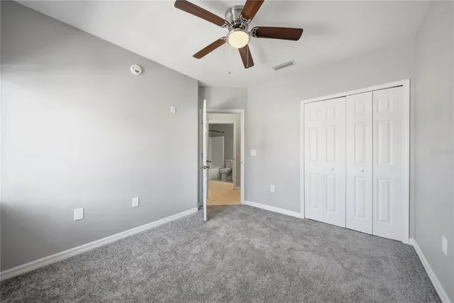 an empty room with closet and a ceiling fan