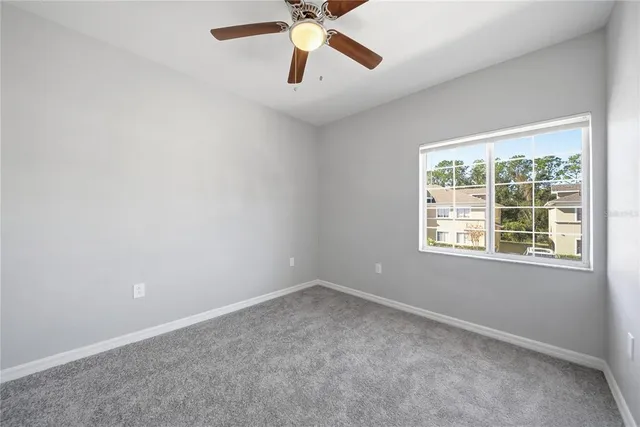 an empty room with a window and a fan