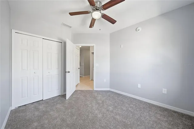 an empty room with closet and a ceiling fan