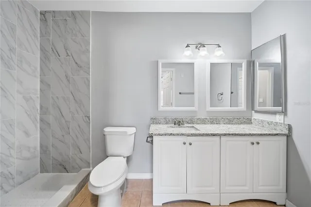 a bathroom with a granite countertop sink a toilet and a mirror