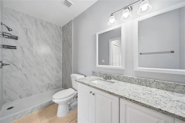 a bathroom with a granite countertop sink a toilet and shower