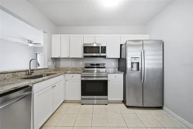 a kitchen with stainless steel appliances granite countertop a stove a sink and a refrigerator