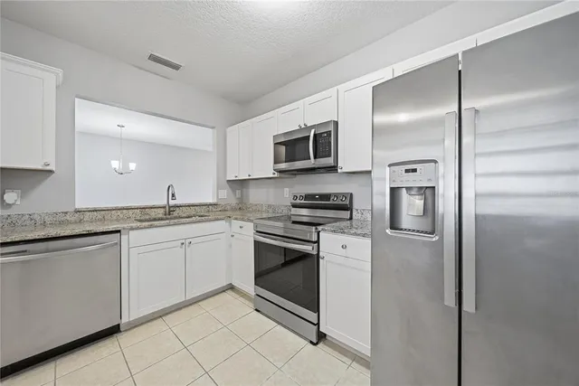 a kitchen with stainless steel appliances granite countertop a refrigerator and a stove top oven