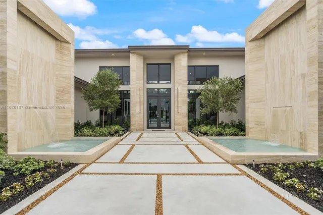 a front view of a house with a yard and potted plants
