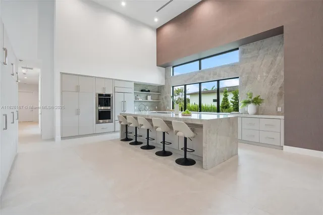 a large kitchen with kitchen island a large counter top space and stainless steel appliances