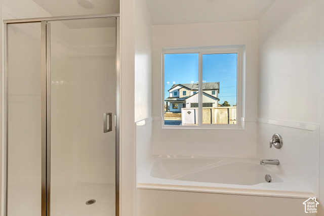 3357 South 960 West Logan, UT 84321 - Photo 9 of 17 White soaking tub with chrome fixtures, an adjacent shower with a clear glass enclosure, and a window providing natural light