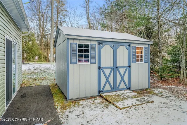 a view of a grey house with large windows and a yard