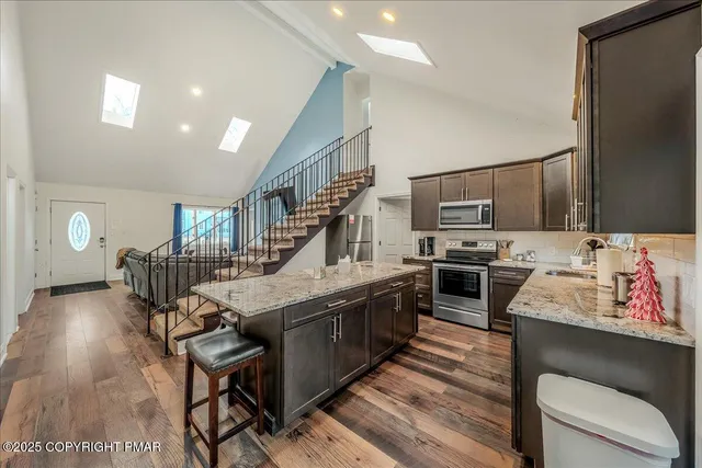 a kitchen with stainless steel appliances kitchen island granite countertop a table chairs in it and wooden floors