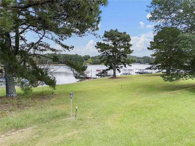 a front view of a house with a garden and lake view
