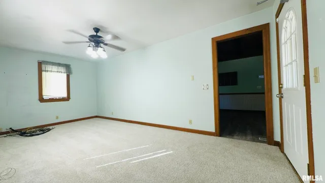 an empty room with windows and ceiling fan