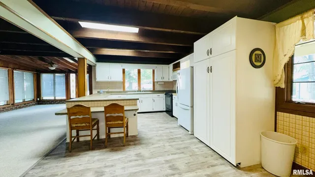 a kitchen with stainless steel appliances a refrigerator a sink a stove and white cabinets with wooden floor