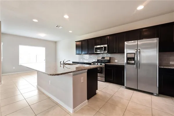 a kitchen with stainless steel appliances granite countertop a refrigerator and a sink