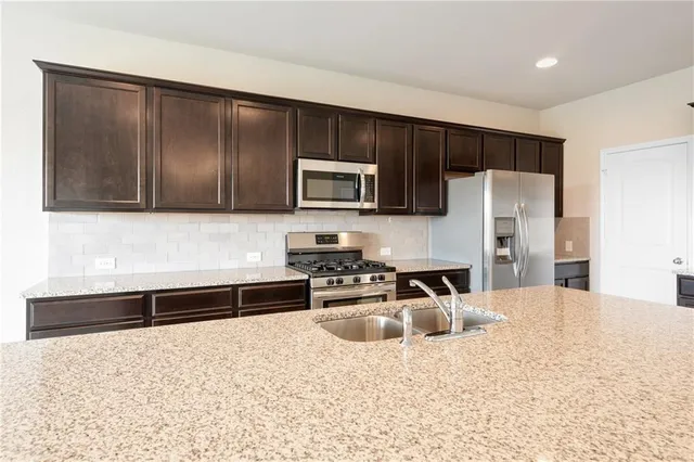 a kitchen with granite countertop a refrigerator stove and microwave