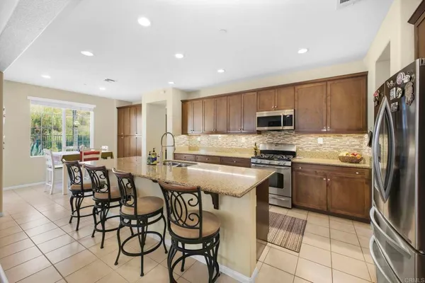 a kitchen with stainless steel appliances a refrigerator a stove a sink dishwasher with a dining table and chairs