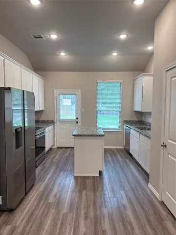 a kitchen with a refrigerator and white cabinets