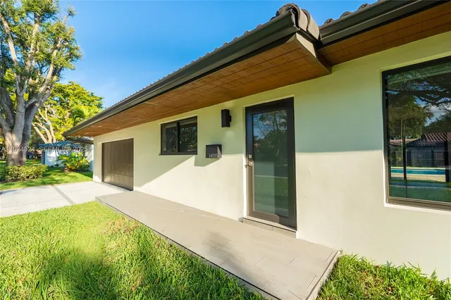 a front view of a house with a yard and potted plants