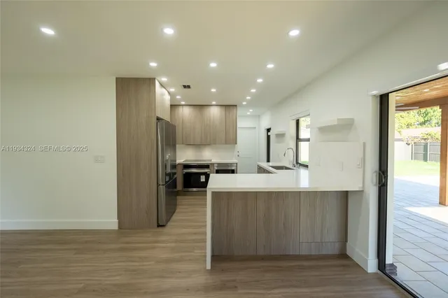 a view of kitchen with stainless steel appliances refrigerator sink and cabinets