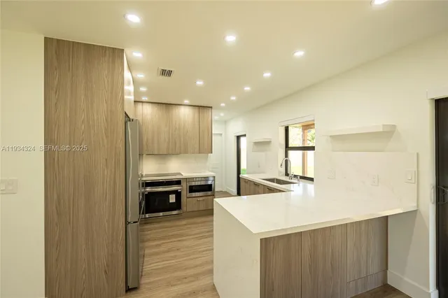 a view of a kitchen with a sink and dishwasher a refrigerator with wooden floor
