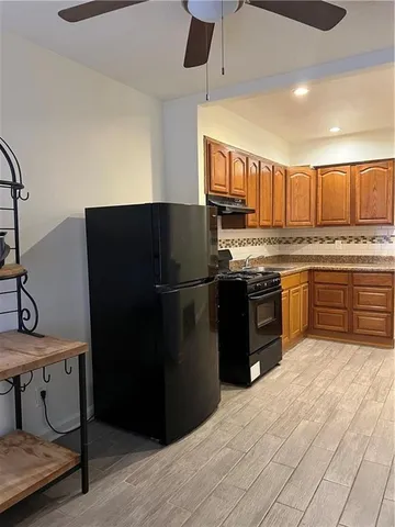 a kitchen with stainless steel appliances granite countertop a refrigerator a sink a stove and a wooden floors