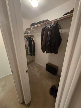 a view of walk in closet with clothes and shoes