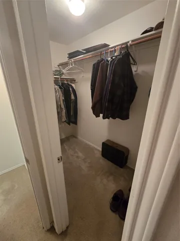 a view of walk in closet with clothes and shoes