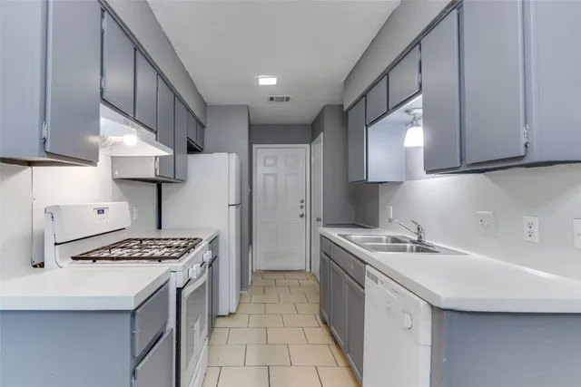 a kitchen that has a sink a stove and a refrigerator