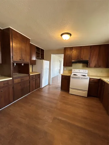 a kitchen with granite countertop a refrigerator and a stove top oven
