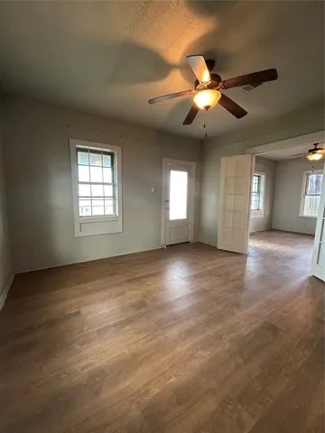 a view of an empty room with window and wooden floor