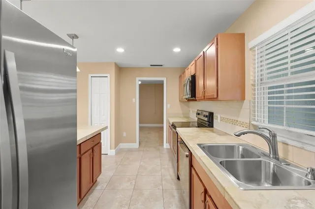 a kitchen with stainless steel appliances granite countertop a stove top oven a sink a refrigerator and a oven