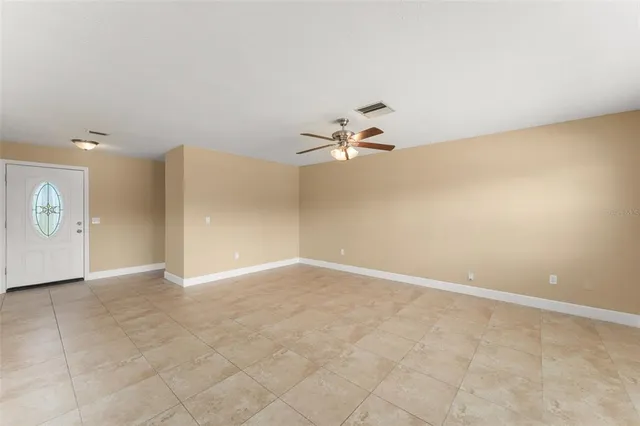 en empty room with windows and chandelier fan