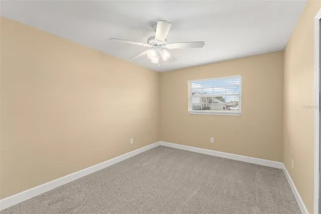 an empty room with a window and ceiling fan