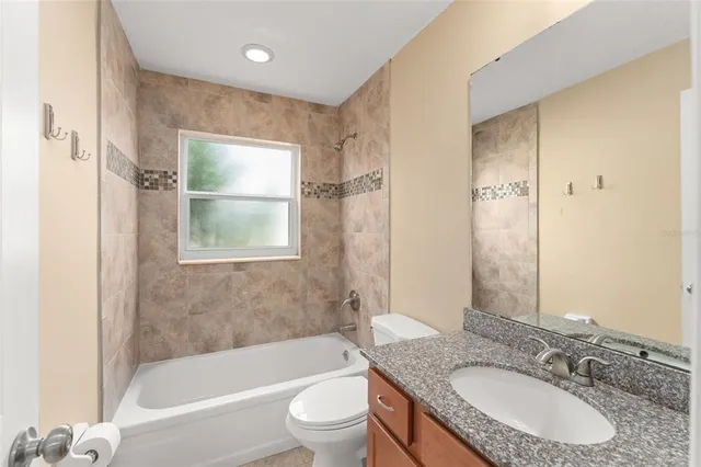 a bathroom with a granite countertop toilet a sink and a bathtub