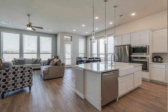 a large white kitchen with lots of counter space a refrigerator a couch and wooden floor