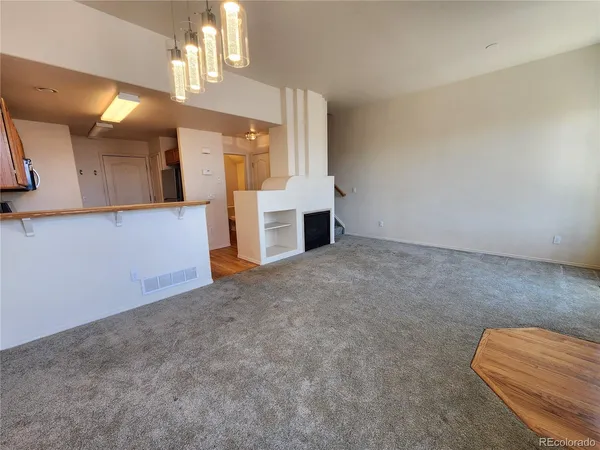 a view of an empty room with window and a kitchen