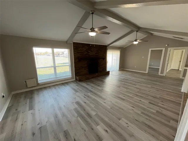 an empty room with wooden floor chandelier and windows