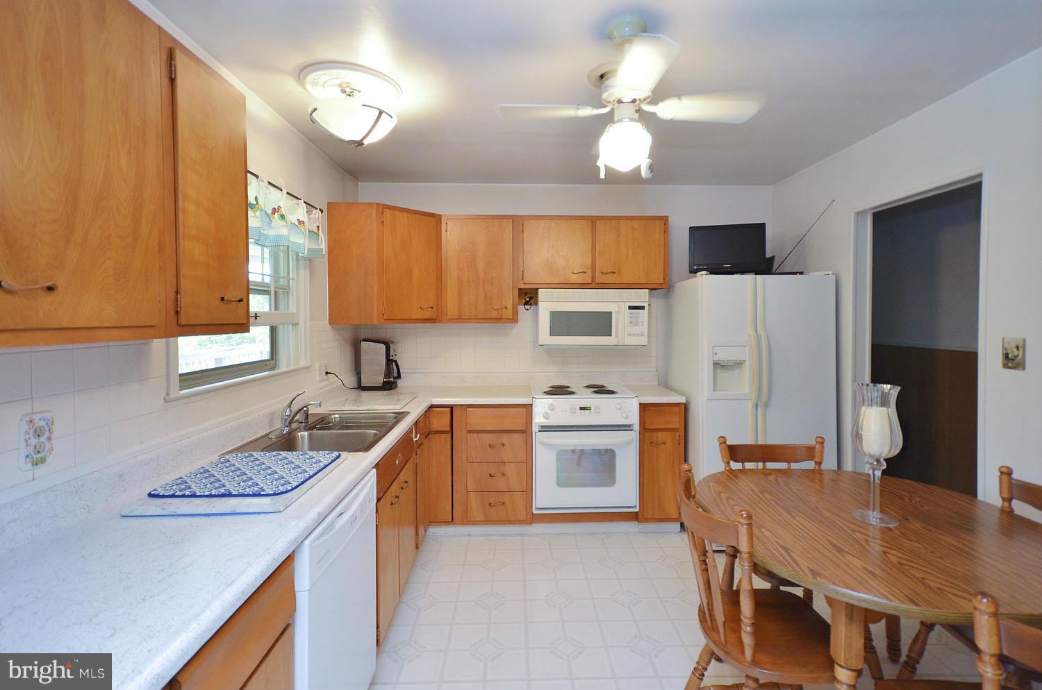 1008 South Hoga Road Sterling, VA 20164 - Photo 7 of 30 a kitchen with stainless steel appliances granite countertop a stove top oven a refrigerator a sink dishwasher with a dining table and chairs